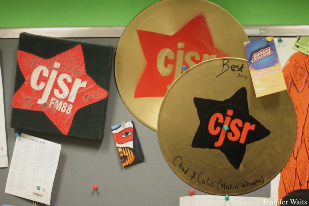 Photo of wall at CJSR-FM. Gold-painted records are decorated with CJSR logo. Photo: J. Waits